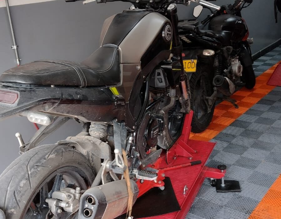 Mecánico trabajando en motocicleta con logo de Motocyclón Serviteca Club
